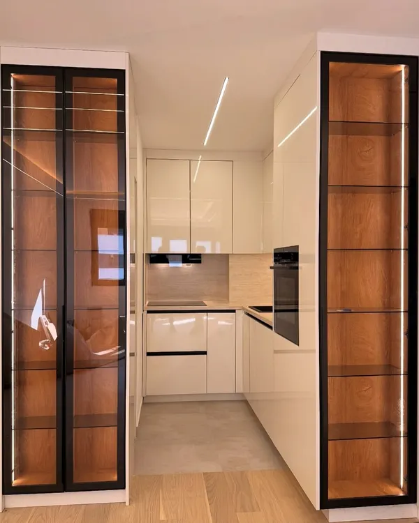 This is our signature modern kitchen design, featuring high-gloss handleless cabinets and integrated tall units for a seamless look. We've used profile LED lighting to create a warm ambiance and highlight the clean lines, showing how we blend premium aesthetics with practical design for Indian homes.