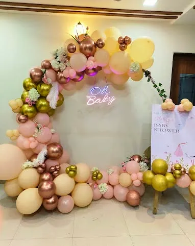 A popular choice for baby showers, this circular balloon arch features an "Oh Baby" neon sign. The color palette of peach, rose gold, and soft yellow creates a warm and celebratory atmosphere, complemented by a matching welcome sign.