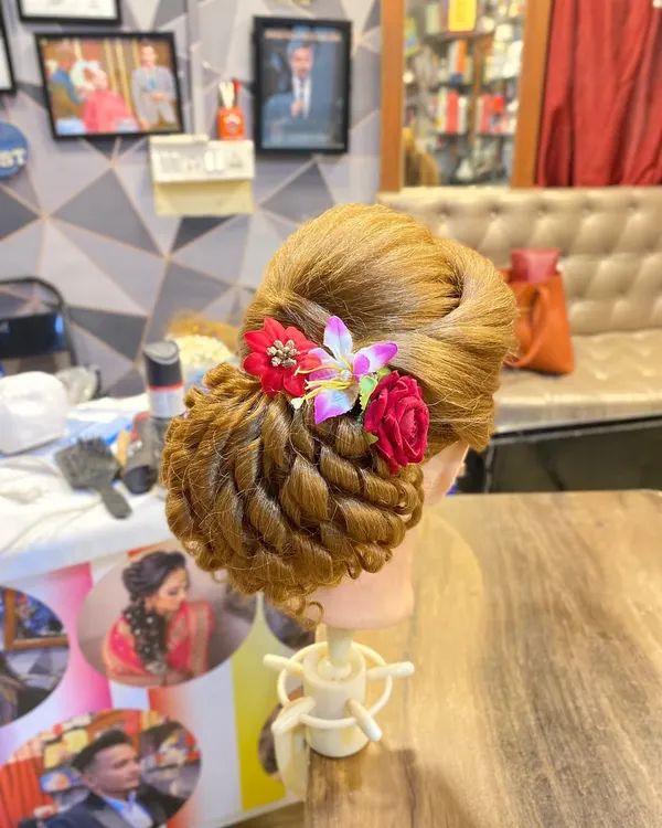 A creative updo on a mannequin, showcasing a twisted bun technique decorated with flowers. This is a style I teach in my advanced classes.