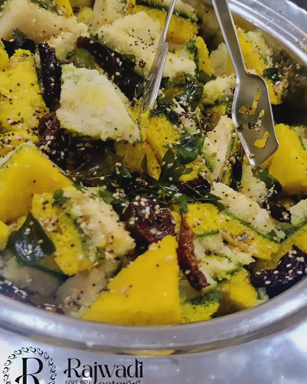 A close-up of our soft and spongy Khaman Dhokla, a classic Gujarati snack. It's tempered with mustard seeds and curry leaves, showcasing our commitment to authentic flavors.
