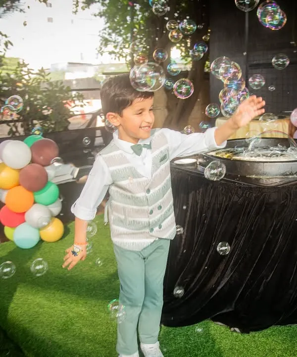 Pure joy. The birthday boy has a blast playing with a bubble machine, a perfect candid moment from his outdoor party.