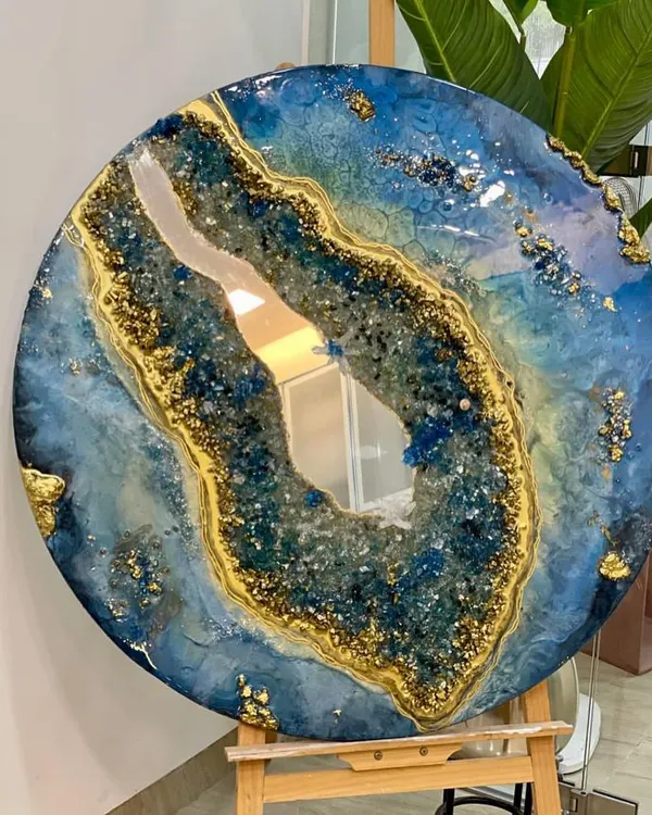 This circular geode-inspired mirror showcases the beauty of resin art, blending deep blues and brilliant golds with genuine crystals. It's a perfect example of the kind of luxurious, high-end decor piece you can learn to create, adding a statement to any wall.