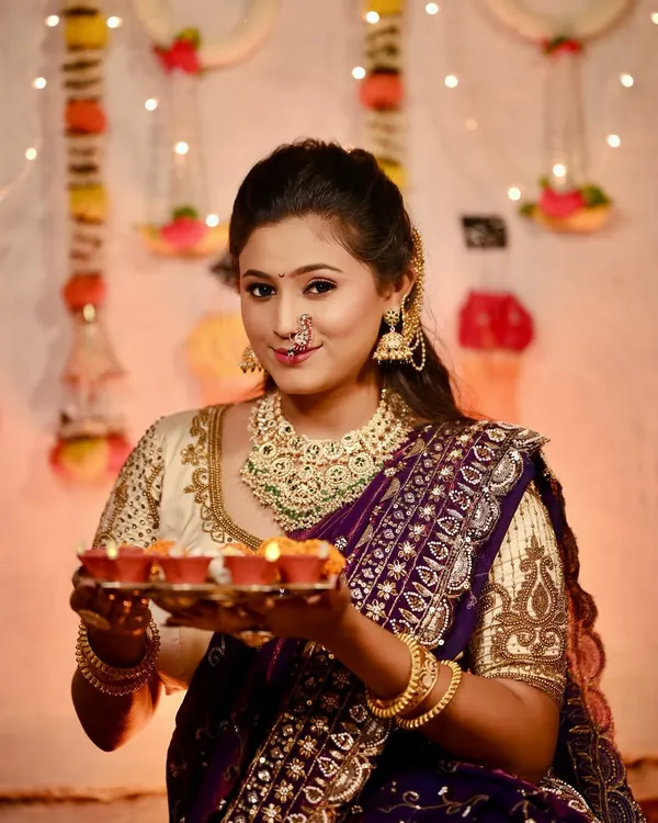 A perfect Diwali look. This model is holding a plate of diyas, wearing a rich purple Nauvari with a heavily embroidered cream blouse and matching jewellery.
