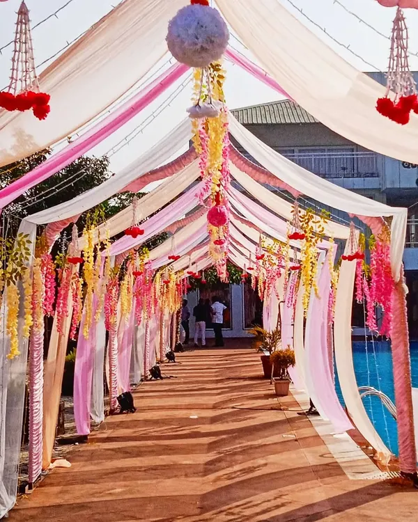 A beautiful draped walkway for a poolside event. I used flowing drapes in shades of pink, white, and yellow, with hanging floral strings to create a dreamy entrance path.