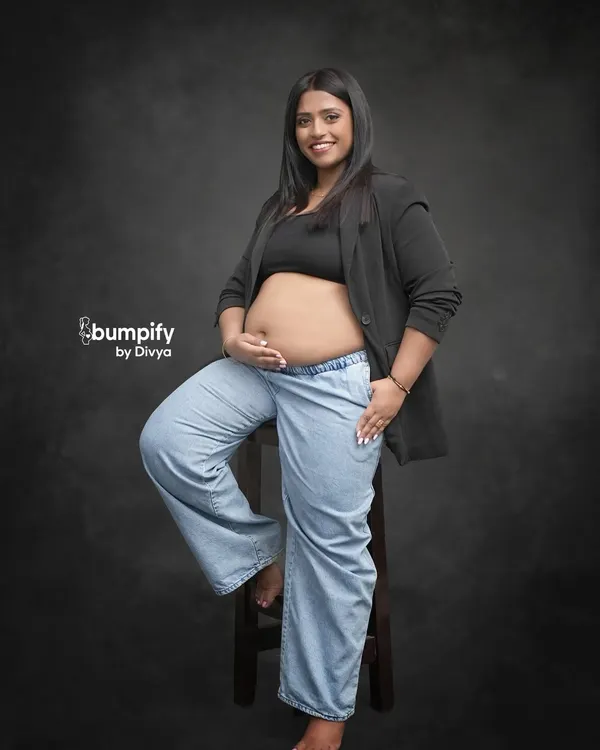 Maternity photos can be modern and chic too. This mom-to-be rocks a casual look with a blazer and jeans, showing off her beautiful bump with confidence and style against a classic studio backdrop.