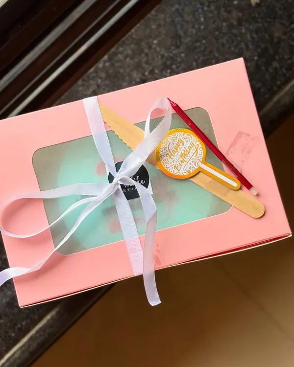 An example of my beautifully packaged bento cakes. This minimal light blue cake is presented in a pink box with a window, tied with a white ribbon, and includes a wooden knife and a birthday candle.