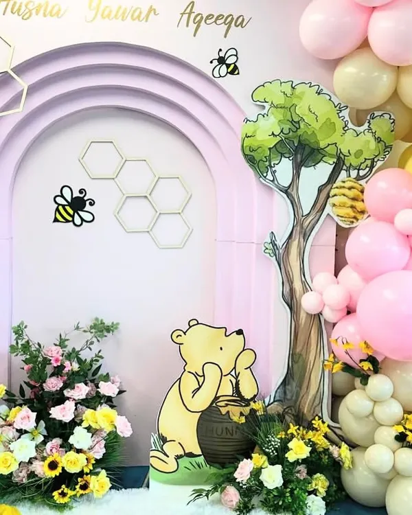 A sweet Winnie the Pooh themed Aqeeqa ceremony. This close-up shows the character cutout, beehive details, and a lovely mix of balloons and florals.