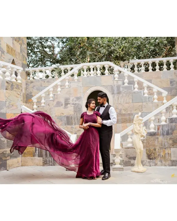 A classic fairytale pose on a grand stone staircase. The bride's magnificent purple gown with its long, flowing trail creates a moment of pure elegance and romance.