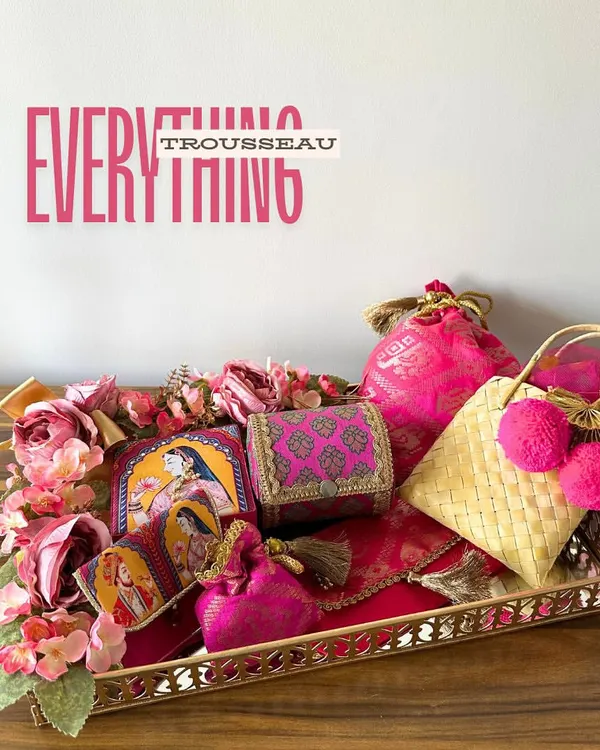 This is my "Everything Trousseau" tray in a regal Rani Pink. It’s a complete set for a bride, featuring a potli, cane bag, bangle case, and more, all curated to bring a touch of royal elegance to her new beginning.