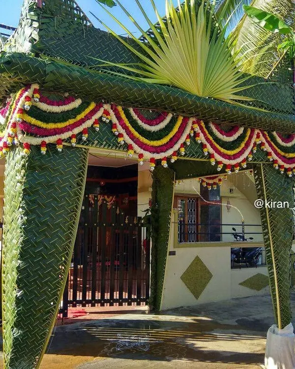 A traditional 'chapra' canopy made entirely of woven green coconut leaves and decorated with floral garlands. This eco-friendly design is perfect for auspicious occasions like housewarmings.