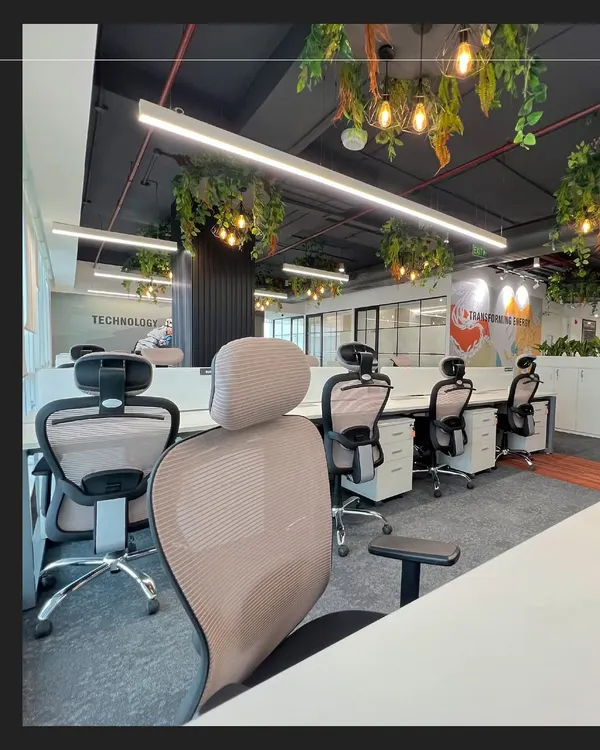 An open-plan workspace at the Rays Power office, featuring ergonomic chairs and integrated planters on storage units. We incorporated biophilic design with hanging plants to improve air quality and create a calming atmosphere for employees.
