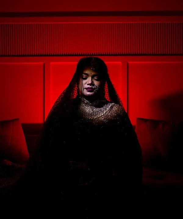 A moment of quiet reflection. This artistic bridal portrait uses deep red tones and shadows to create a sense of mystery and elegance, focusing on the bride's serene expression.