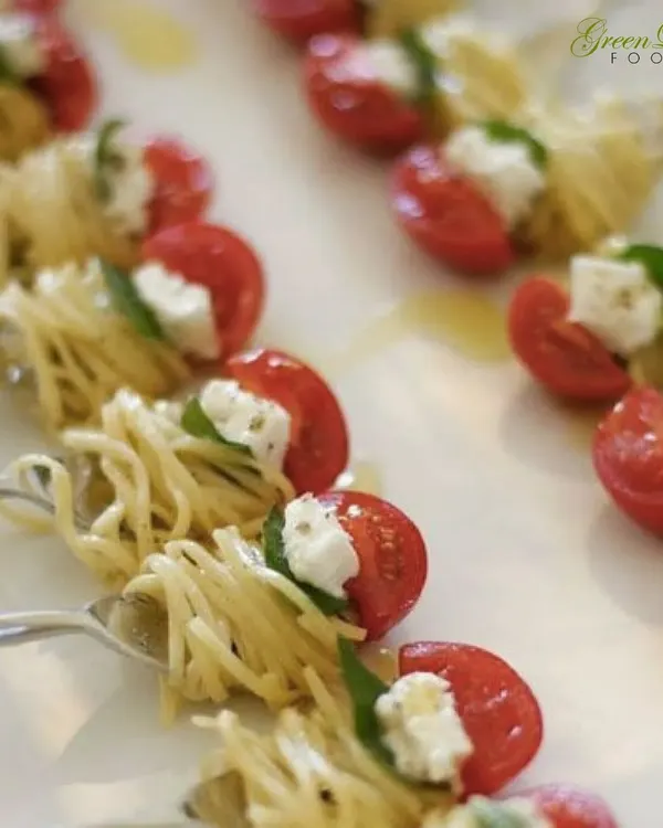 An Italian classic reimagined as a perfect bite. These spaghetti nests with cherry tomato and fresh cheese are served on forks for an elegant, mess-free appetizer experience.