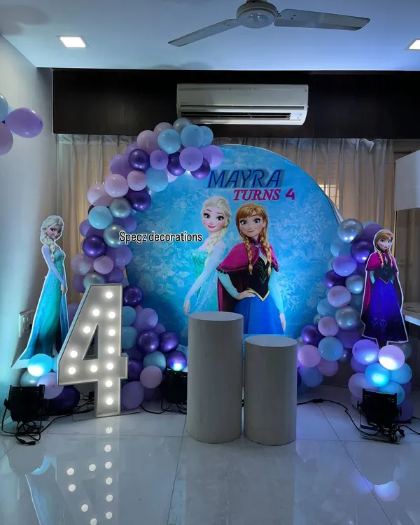 A complete Frozen-themed party setup for Mayra's 4th birthday. The circular backdrop, character cutouts, and purple and blue balloon arch bring the magic of Arendelle to life.