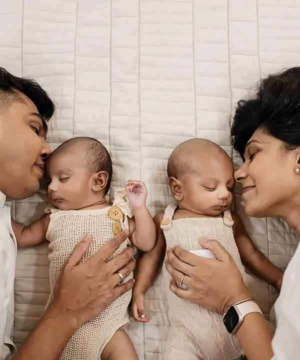 Capturing the complete family with newborn twins is a special honor. This lifestyle portrait shows the beautiful bond and symmetry as parents gaze lovingly at their babies.