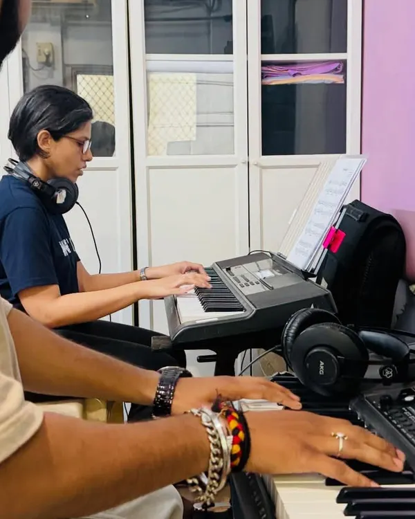 A student receives guidance from a coach during a keyboard lesson. This side-by-side teaching approach ensures that students learn correct posture and hand positioning from the very beginning.
