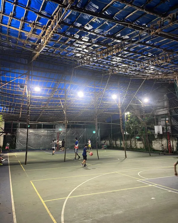 A wide view of our covered basketball court during an evening session. The bright lighting and protected space allow for focused training at any time of day, regardless of the weather.