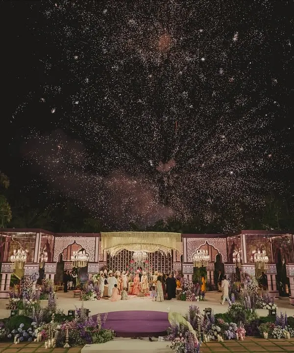 This is the moment that takes your breath away. A grand wedding stage set against the night sky, illuminated by a cascade of fireworks, capturing the scale and magic we bring to your most important day.