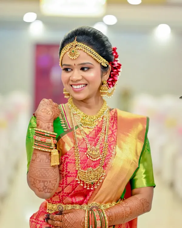 This bride is wearing a full temple jewellery set, including a statement choker, a layered haaram, and a matching oddiyanam (waist belt). It’s a popular choice for achieving that authentic, grand bridal look.