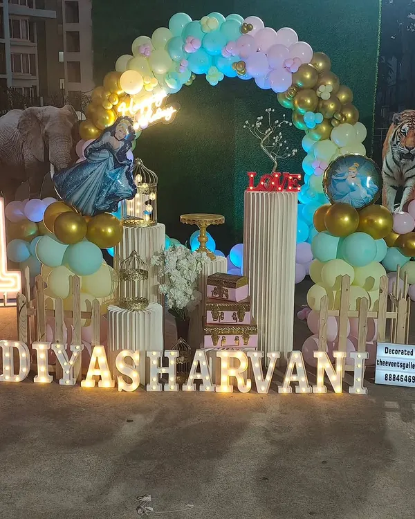 This outdoor first birthday setup shows how I can create a large, detailed scene. It features a custom pastel and gold balloon arch, marquee lighting with the name and age, and themed cutouts to bring the party to life.