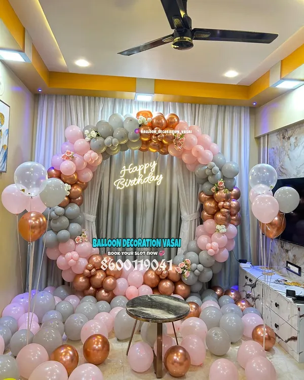 A beautiful circular balloon arch in pastel pink, grey, and rose gold. The "Happy Birthday" neon sign in the center makes it a perfect, modern backdrop for a birthday party.