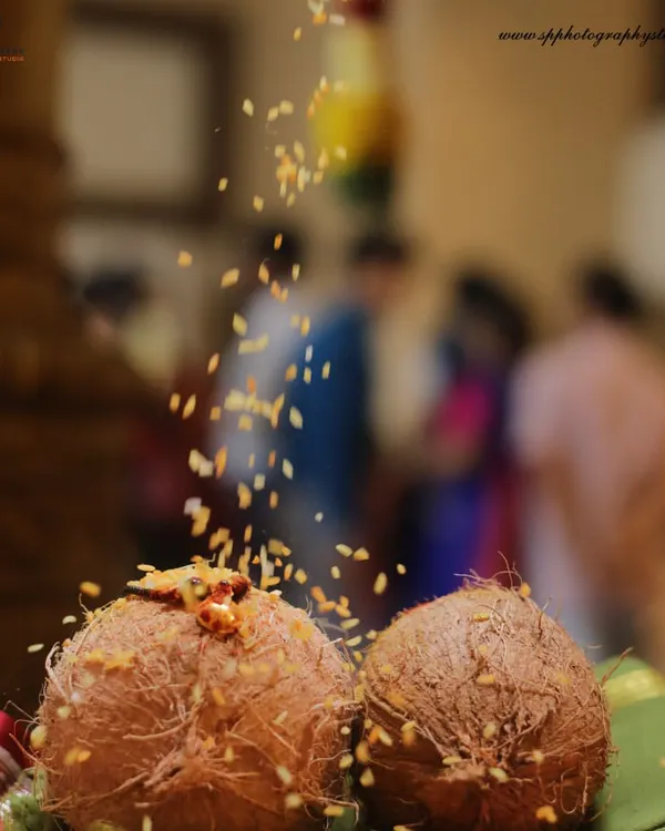 A detail shot of coconuts used in a traditional Hindu ceremony, with rice grains being showered as part of the ritual. We capture the beauty in these symbolic elements.