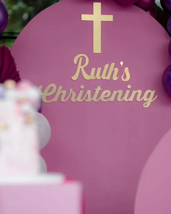 A beautiful Christening setup in a rich magenta. The gold lettering and cross on the arched backdrop create an elegant and celebratory feel for this sacred occasion.