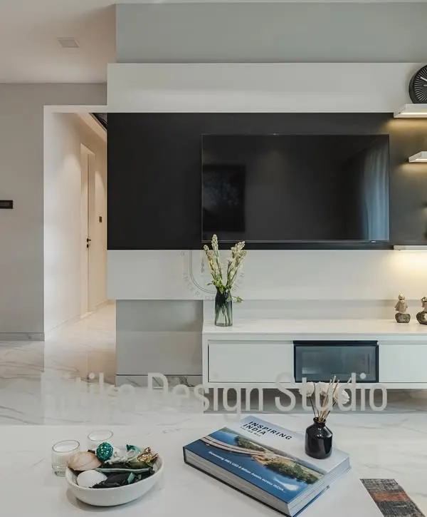 This close-up shows the details of the custom media unit. The combination of a black panel, a floating white console, and open, backlit shelving creates a design that is visually light yet provides ample space for electronics and decor.