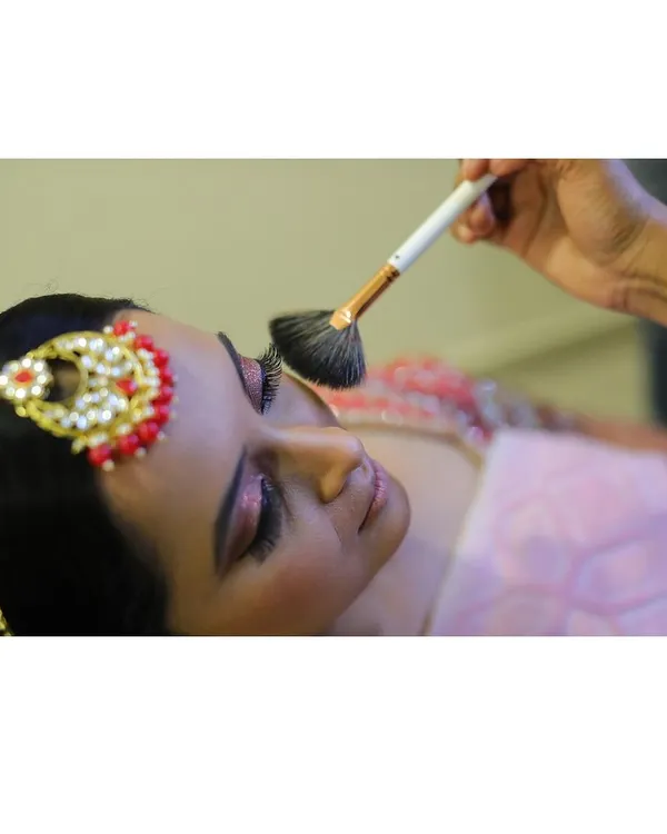 A close-up of the makeup application process. Here, I'm using a fan brush to lightly apply setting powder, ensuring the makeup stays flawless all day long.