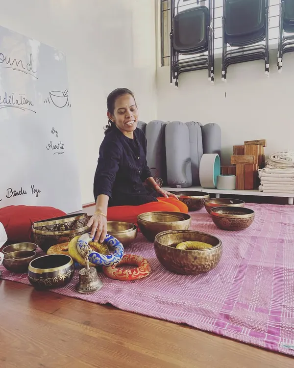 Our sound meditation facilitator, Aarthi, prepares for a session. Each bowl is carefully selected and placed to create a layered, harmonious experience that guides participants into deep states of rest and self-healing.