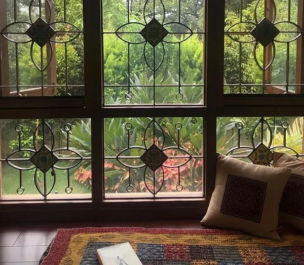 This wide window at the Roopa Hariprasad Residence features a custom-designed grille with floral motifs and inlaid tiles. It frames the view of the garden beautifully, turning the window itself into a piece of art.