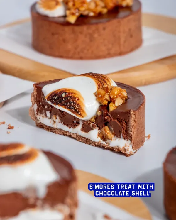 My S'mores Tart is a sophisticated take on a campfire classic. A crisp chocolate shell holds a molten dark chocolate ganache, hazelnut praline, and is topped with a toasted marshmallow swirl.