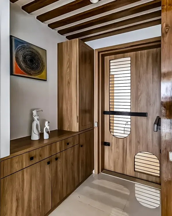 We designed this entryway with floor-to-ceiling wooden storage, including a console table with drawers and a tall cabinet. The custom-designed main door with slatted details complements the furniture, creating a warm and cohesive entrance.