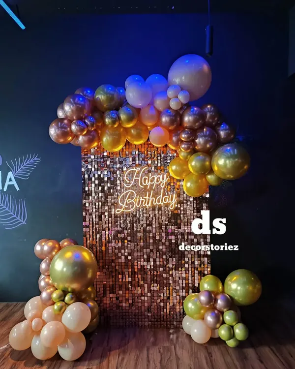 We love creating glamorous party backdrops like this shimmering gold sequin wall. Paired with a 'Happy Birthday' neon sign and a cascade of metallic balloons, it creates a fantastic focal point.