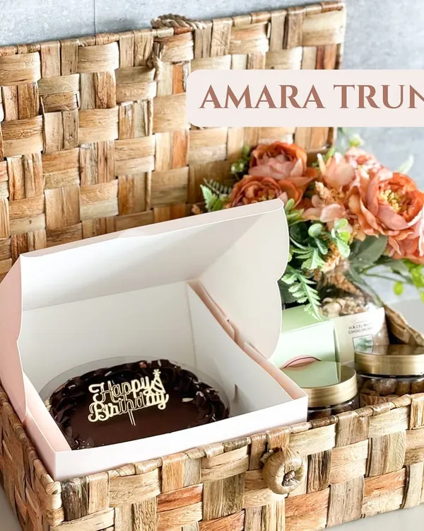 Our Amara Trunk is the perfect birthday surprise. It features a rich chocolate cake with a "Happy Birthday" topper, nestled inside a reusable wicker trunk with other gourmet goodies.