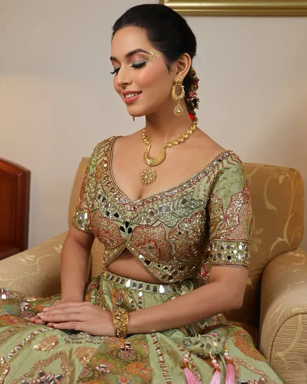 This Mehendi look is designed to be memorable. The eye makeup features playful studs and gold dust, creating a sparkling effect that catches the light beautifully during a day function.