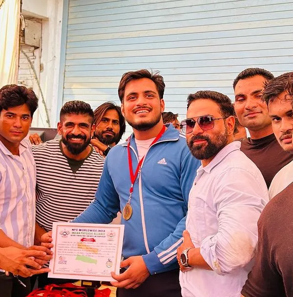 Receiving my first-place certificate at the NPC district bench press powerlifting competition in Alwar.