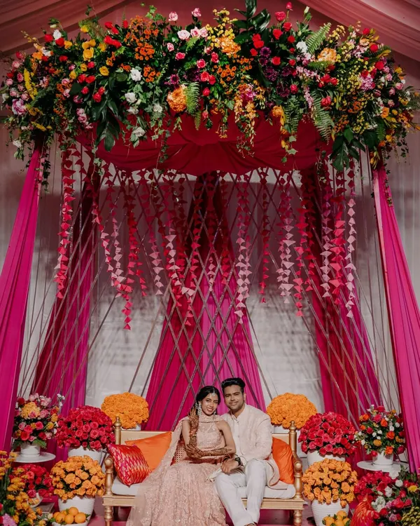 The centerpiece of our 'Hues of Love' Mehendi was this stunning seating area for the couple. Draped in vibrant pink fabric and crowned with a lush canopy of fresh flowers, it was the perfect spot for photos and rituals.