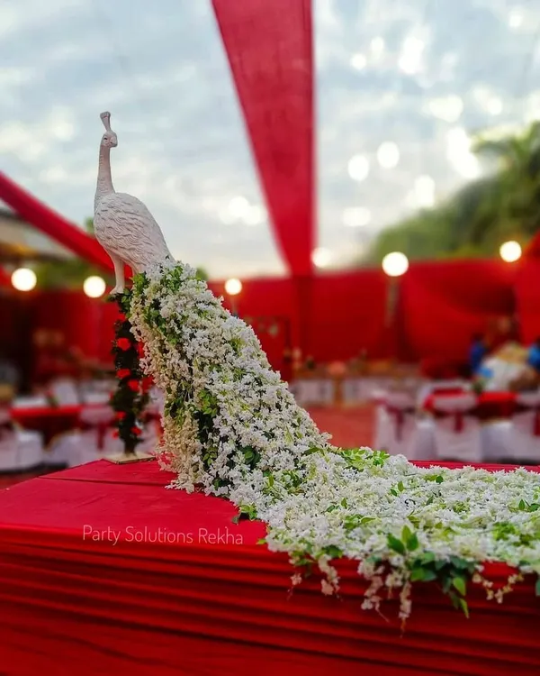 This elegant white peacock sculpture makes a stunning centerpiece or accent piece for any event. Its long, flowing tail is meticulously crafted from hundreds of fresh white flowers and green leaves, creating a piece of living art.