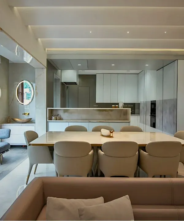 An integrated living and dining area where a neutral palette is warmed by natural wood and abundant light. The open-plan layout connects the sleek, modern kitchen to the rest of the home, making it perfect for both daily life and entertaining.
