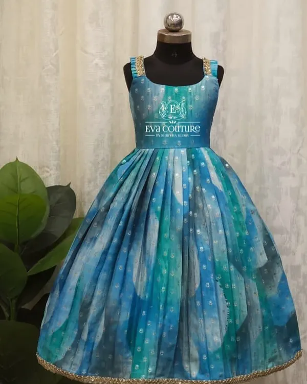 A beautiful sleeveless gown in shades of blue and green. The pleated skirt gives it a lovely flare, and the gold lace straps add a touch of sparkle.