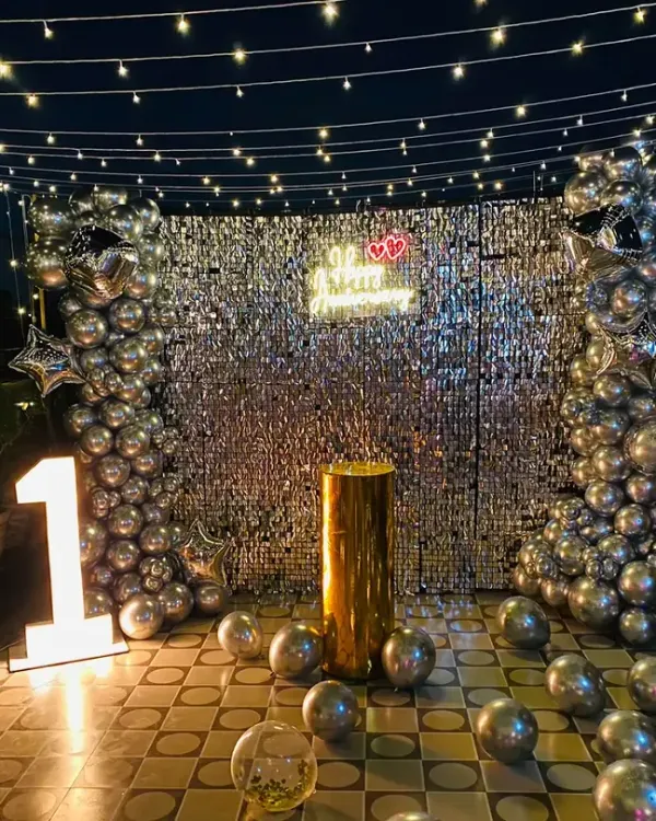 A beautiful terrace setup for a first anniversary. I used a silver shimmer wall, marquee lights for the number '1', and lots of silver balloons to create a magical, open-air celebration space.