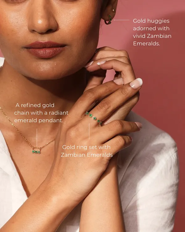 The Petit Emerald Set is the definition of understated elegance. This image shows the complete set worn together: a refined gold chain with an emerald pendant, matching gold huggies, and a delicate ring.