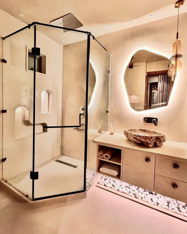 This bathroom is designed to feel like a private, natural spa. I used a custom-carved stone sink and an organically shaped, backlit mirror to create a focal point. The lime-washed walls and soft lighting complete the feeling of a serene escape, bringing the 'sukh and sukoon' of nature indoors.