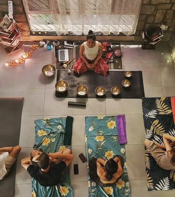 An aerial view of an intimate sound bath session held in a beautiful stone-walled studio. Participants are resting comfortably as one of my certified students facilitates the session, demonstrating the supportive community we build.