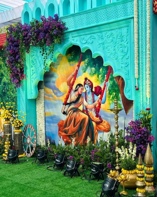 The centerpiece of our Vrindavan theme: a beautiful painting of Radha and Krishna on a swing, framed by a custom-carved arch and lush floral decor.