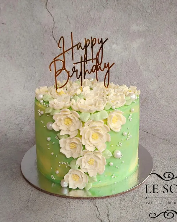 I was so happy with how the buttercream flowers turned out on this cake. This half-kg Biscoff cake features a cascade of hand-piped white and green flowers against a soft green background.