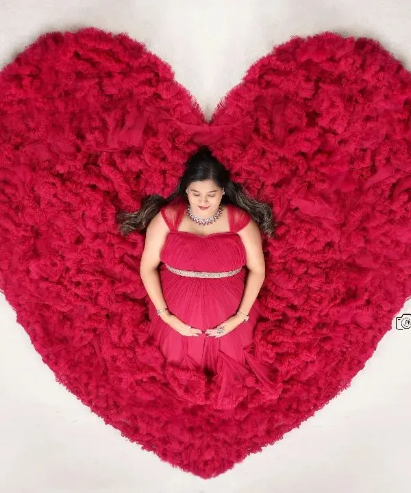 Our signature overhead studio shot, with the mother-to-be peacefully lying in a heart-shaped arrangement of a red ruffled gown.