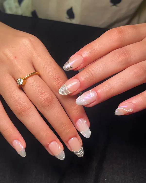 A beautiful bridal set featuring a mix of styles. Some nails have delicate silver line work, while others have a pearlescent chrome finish and tiny pearl accents.