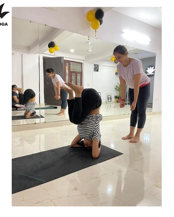 My approach is completely personal. Here, I'm providing hands-on assistance to ensure proper alignment and safety in a headstand, making sure the practice is tailored to your body and your goals.